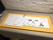 Using the foam board cutouts to position the letters on the base plate. Note the very tightly bent strip for the question-mark-dot.